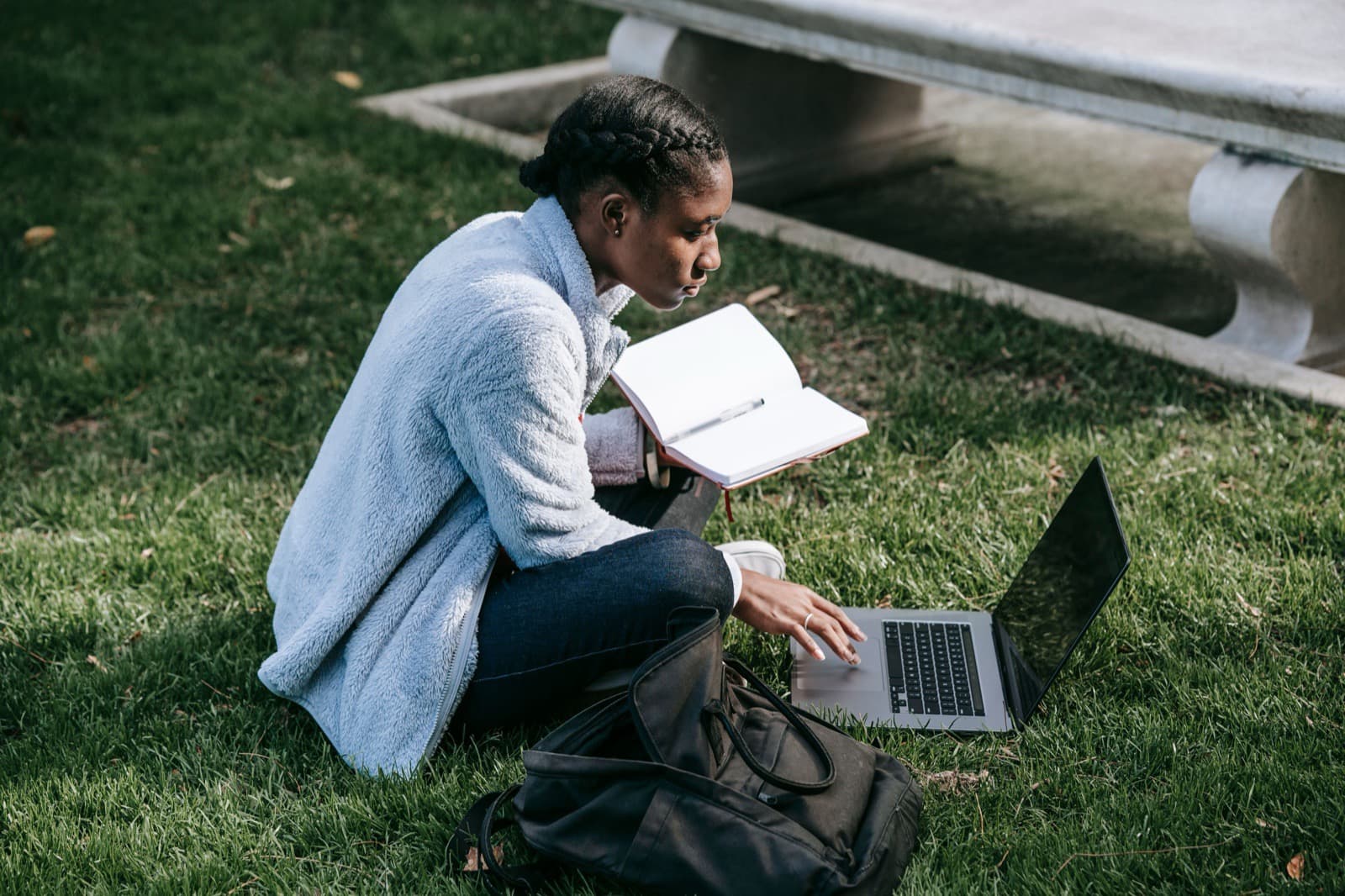 Young adult student studying outdoors with a laptop